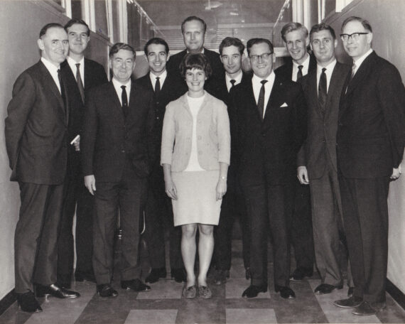 At center of photo, my mother. Around her, ten men. Location is IBM in London, 1966.